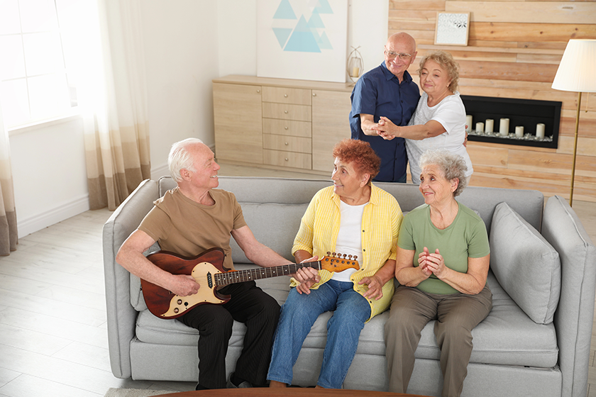 Elderly man playing guitar for his friends 